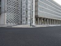 some concrete buildings and streets with a road and some cars parked in front of them