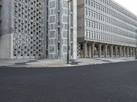 some concrete buildings and streets with a road and some cars parked in front of them