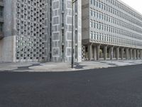 some concrete buildings and streets with a road and some cars parked in front of them