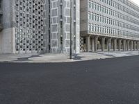 some concrete buildings and streets with a road and some cars parked in front of them