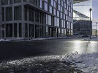 an empty road is in front of a very large office building under construction as the sun rises