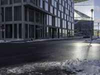 an empty road is in front of a very large office building under construction as the sun rises