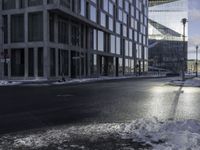 an empty road is in front of a very large office building under construction as the sun rises