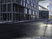 an empty road is in front of a very large office building under construction as the sun rises