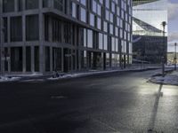 an empty road is in front of a very large office building under construction as the sun rises