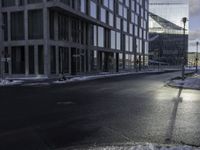 an empty road is in front of a very large office building under construction as the sun rises