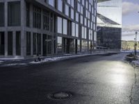 an empty road is in front of a very large office building under construction as the sun rises