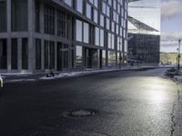 an empty road is in front of a very large office building under construction as the sun rises