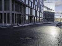 an empty road is in front of a very large office building under construction as the sun rises