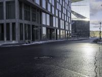 an empty road is in front of a very large office building under construction as the sun rises