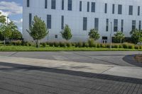 a city street surrounded by grass and tall buildings at the end of a street there is a paved pathway in front of the building