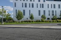 a city street surrounded by grass and tall buildings at the end of a street there is a paved pathway in front of the building