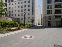 a paved sidewalk in front of two high rise building apartments, with trees in the distance