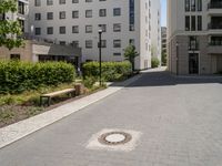 a paved sidewalk in front of two high rise building apartments, with trees in the distance