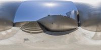 an image of a giant stainless building reflected in a ball in front of some stairs