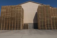 three wooden pallets stacked outside in front of an industrial building with a white sign for an oil company