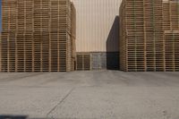 three wooden pallets stacked outside in front of an industrial building with a white sign for an oil company