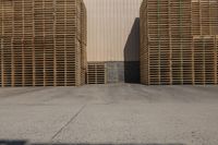 three wooden pallets stacked outside in front of an industrial building with a white sign for an oil company