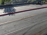 a person riding on the back of a red motorcycle down a road next to a hill