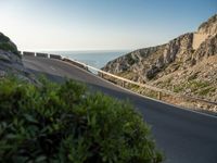 the road to the ocean along the cliffs by the ocean is empty and there are cars on both sides