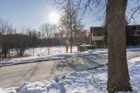 a winter scene with sun shining over the trees and road leading to a parking area