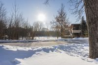 a winter scene with sun shining over the trees and road leading to a parking area