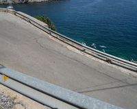 a paved road beside some large boats and a bridge with a bridge to the water