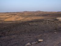 a truck on a dirt road in the desert with rocks and stones on the ground