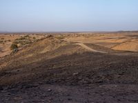 a truck on a dirt road in the desert with rocks and stones on the ground