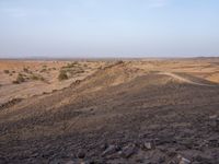 a truck on a dirt road in the desert with rocks and stones on the ground