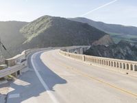 a highway with a sea view below a stone bridge near the ocean and some rocks