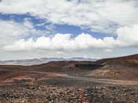 several vehicles are driving in an open space with mountains in the distance and a dirt road