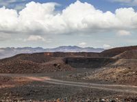 several vehicles are driving in an open space with mountains in the distance and a dirt road