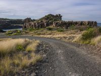 a dirt road winds through an area full of rock formations and vegetation in the distance