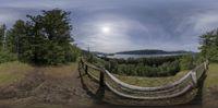 a 360 - camera photo of the ocean, mountains and trees in front of a fence