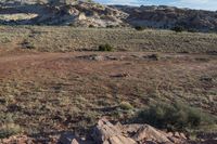 the mountain is covered in barren scrubland next to large boulders and scrublands in the distance, grass and dirt