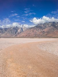 a desert area that is very brown with sand and mountains in the background, there is no one on it