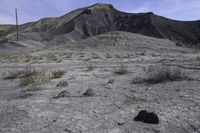 a barren area with dirt and grass and a sky line in the background and rocks