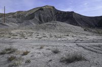 a barren area with dirt and grass and a sky line in the background and rocks