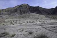 a barren area with dirt and grass and a sky line in the background and rocks