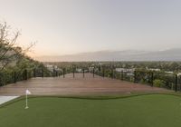 a deck overlooking the golf course and lush greenery, which sits on the edge of a hill