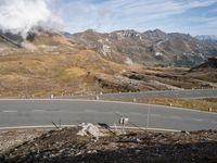 a man is riding a motorcycle on the road while snow capped mountains rise in the background