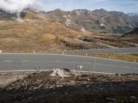 a man is riding a motorcycle on the road while snow capped mountains rise in the background