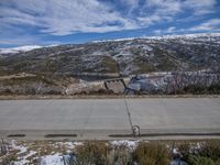 a paved road between two mountain sides that are covered in snow and a lake and a snow covered hill