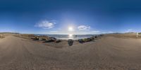 a fish eye view taken from the beach with rocks in the foreground and the ocean on the other side