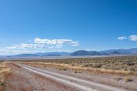 road leading through desert area with clouds in the distance and mountains on either side of it