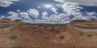 a desert landscape looking up at a highway with clouds in the sky and a sun