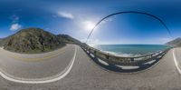 a long curve road with a beautiful ocean in the distance and fisheye lens pointed out to fish eye