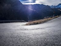 an asphalt highway stretches into the mountains, with a lone man standing by the roadside