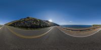 an empty highway stretches along a large cliff and overlooks the ocean below from the hill